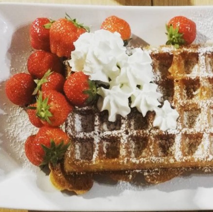 some delicious waffle with strawberries and cream on top